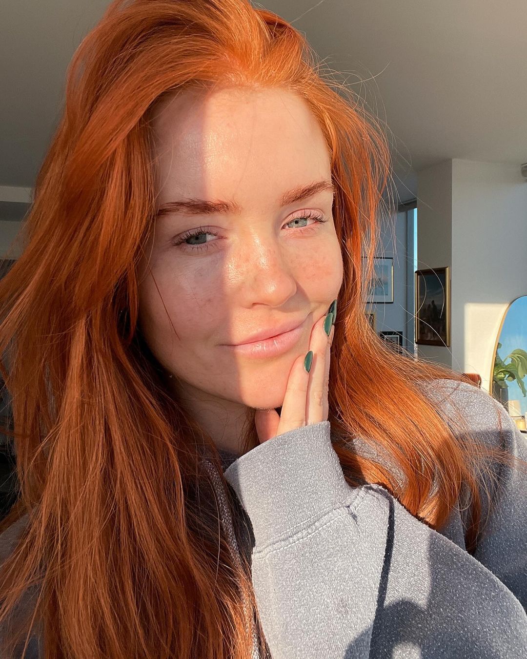 A person basking in the warm glow of the setting sun with auburn hair and a contemplative gaze