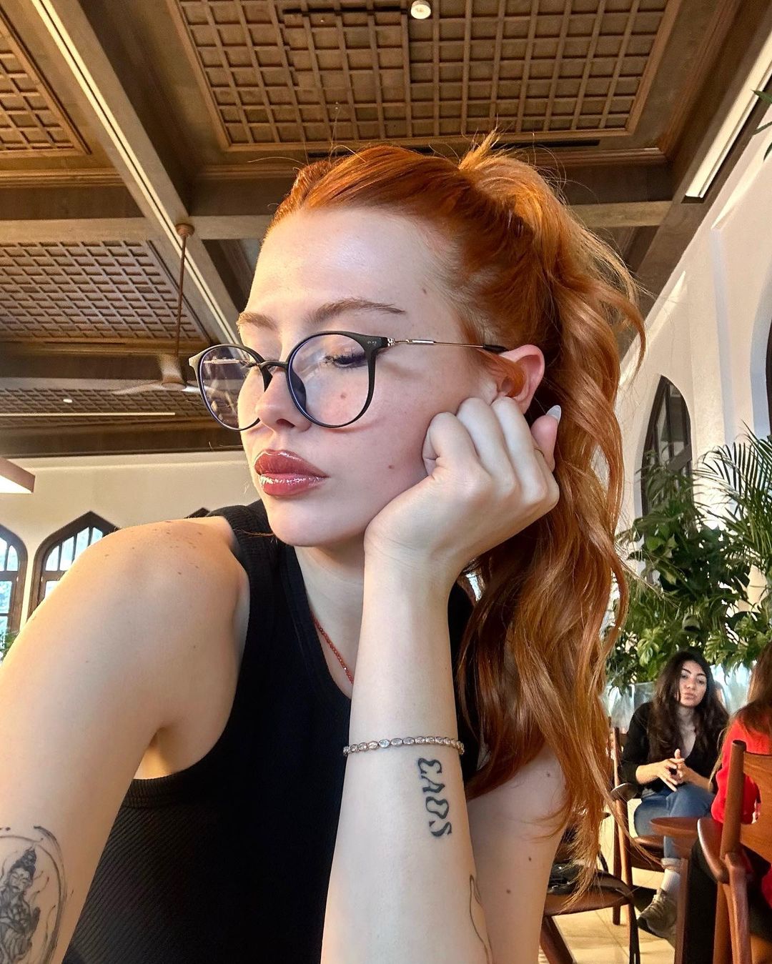 A contemplative woman with red hair sitting in a café