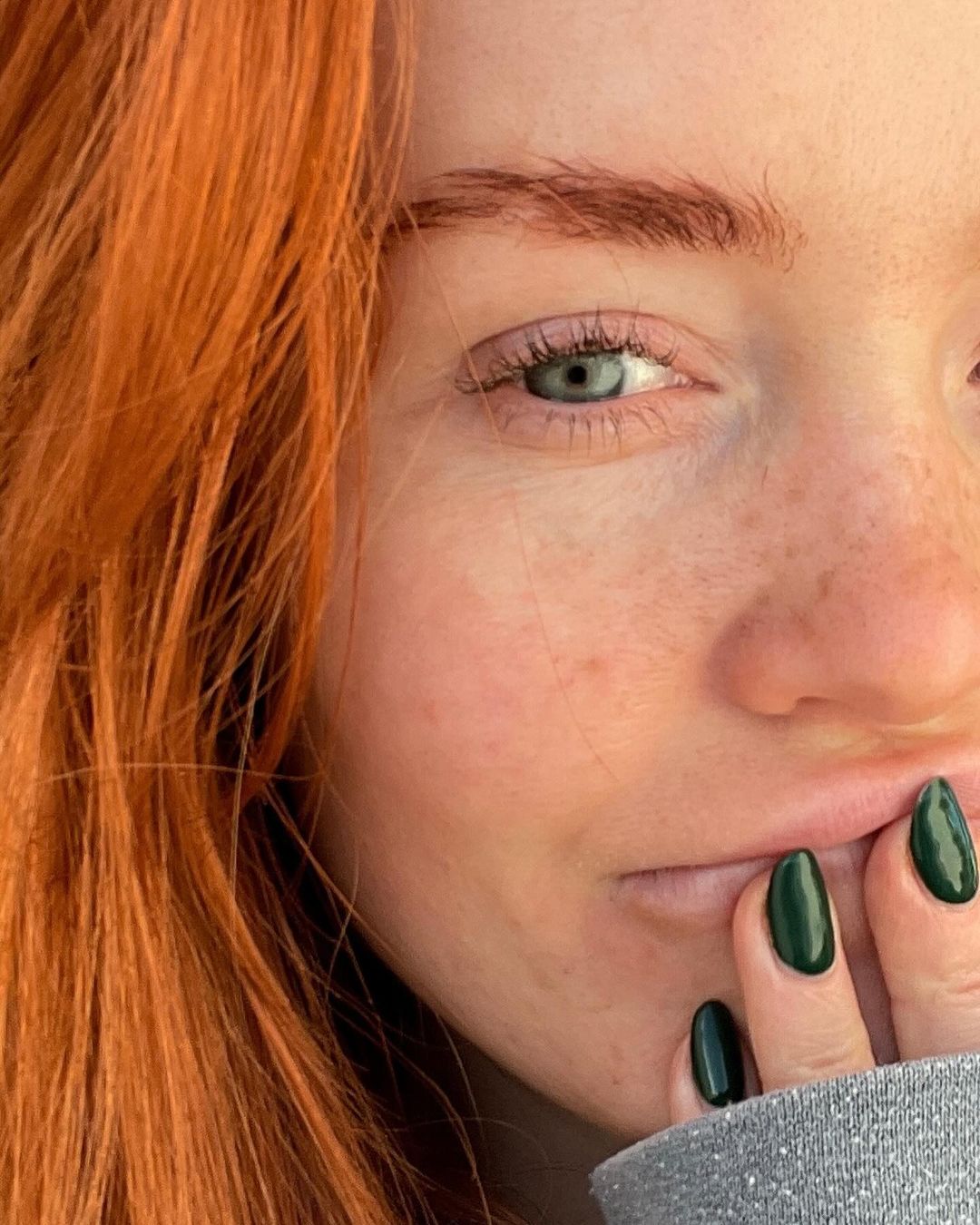 A portrait of a woman with striking red hair and green eyes
