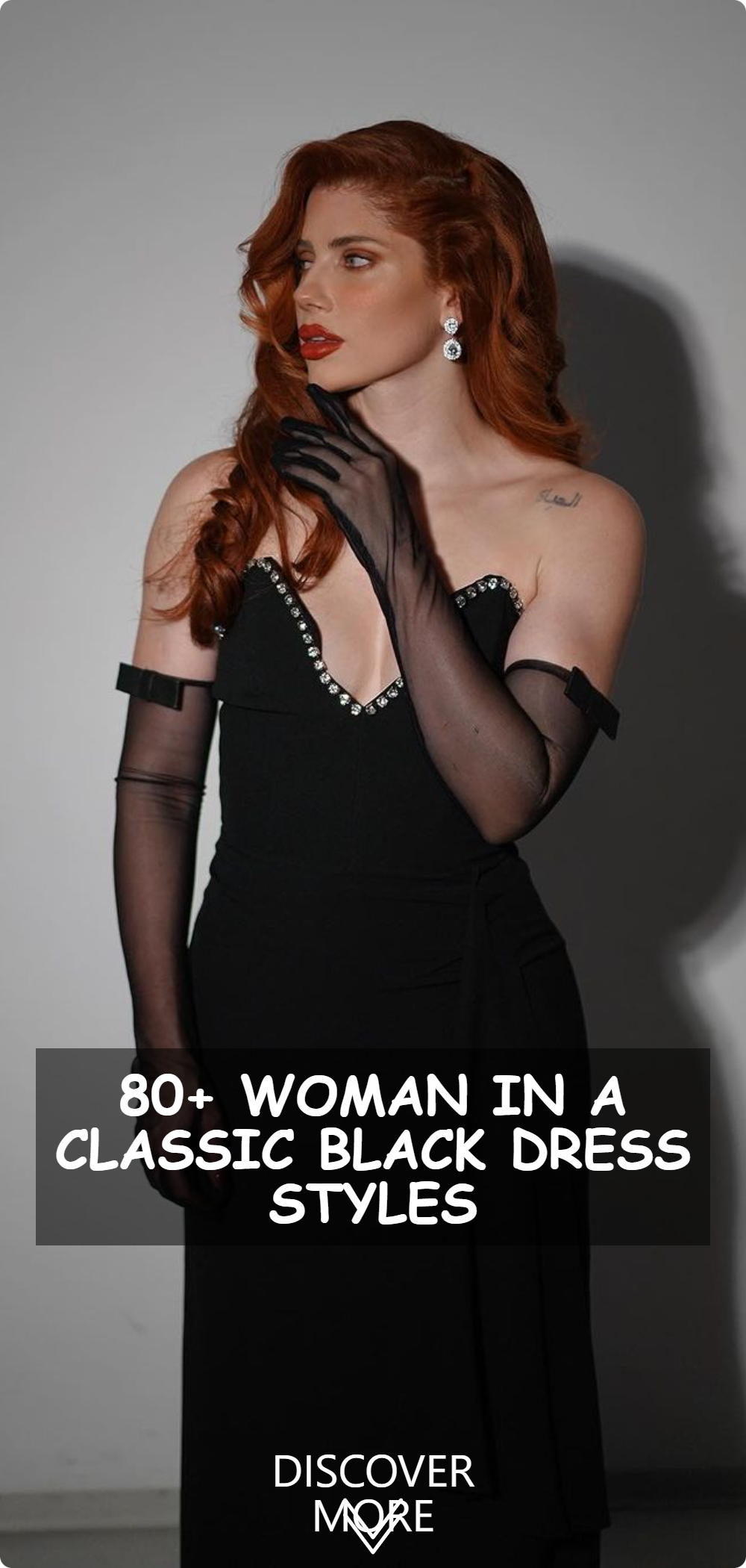 A woman in a classic black dress with unique shoulder straps standing in a pose that exudes confidence and sophistication.