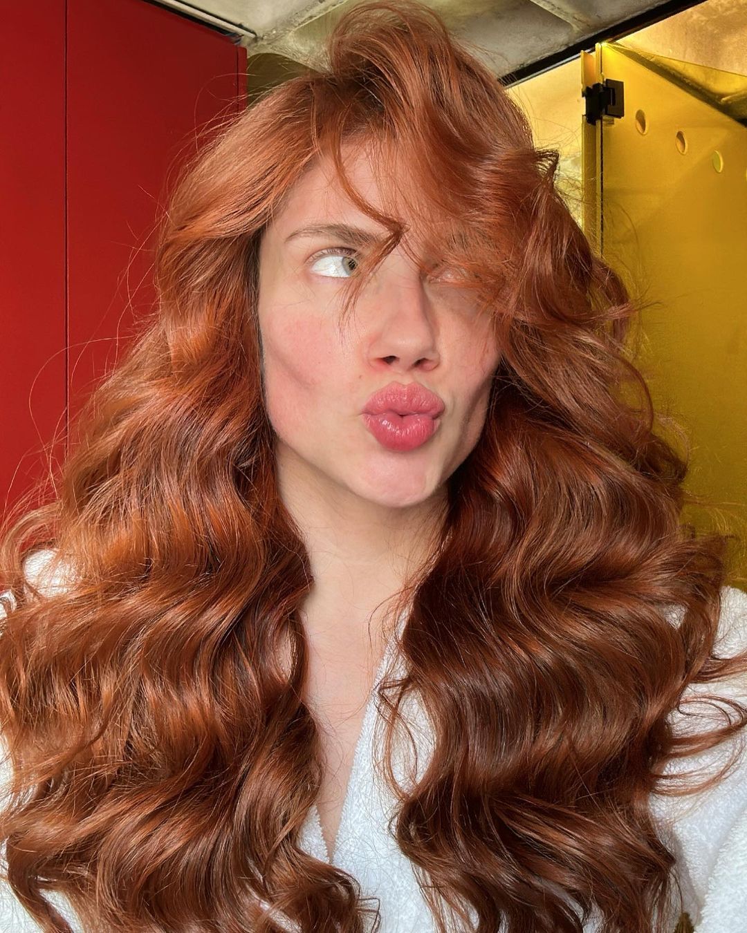 A woman with luscious red hair puckering for a playful selfie